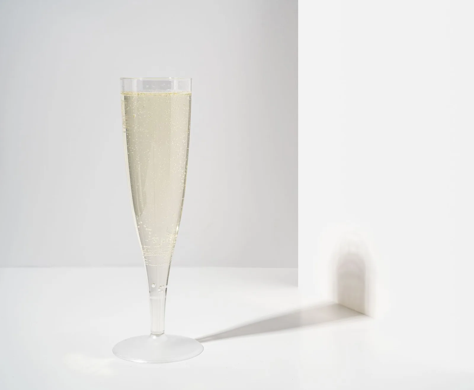 Een slank glas met lichte mousserende wijn in zacht daglicht
