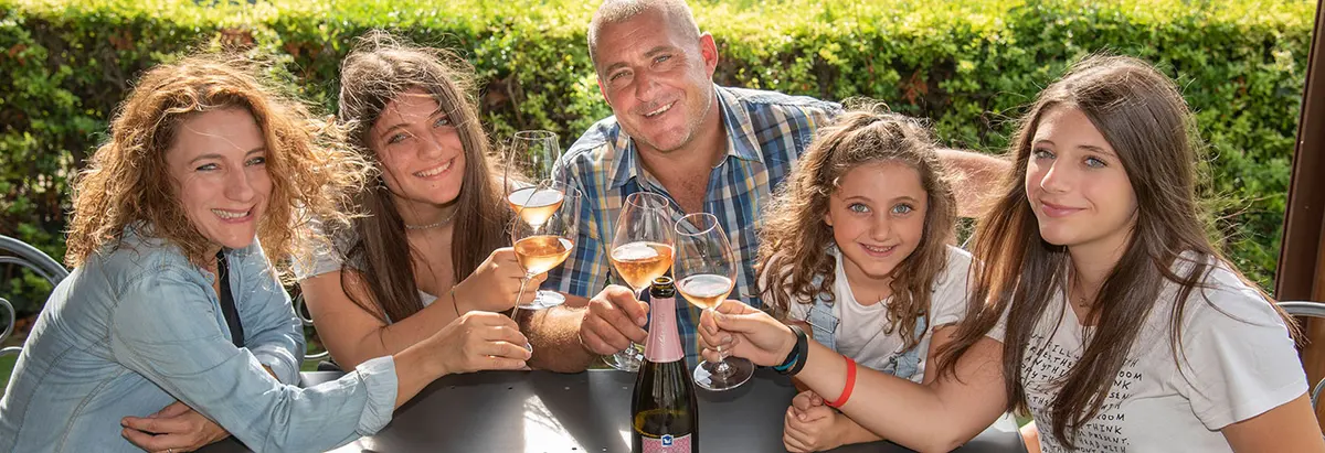 Mensen met wijnglazen aan tafel bij de wijngaarden van Ada Nada